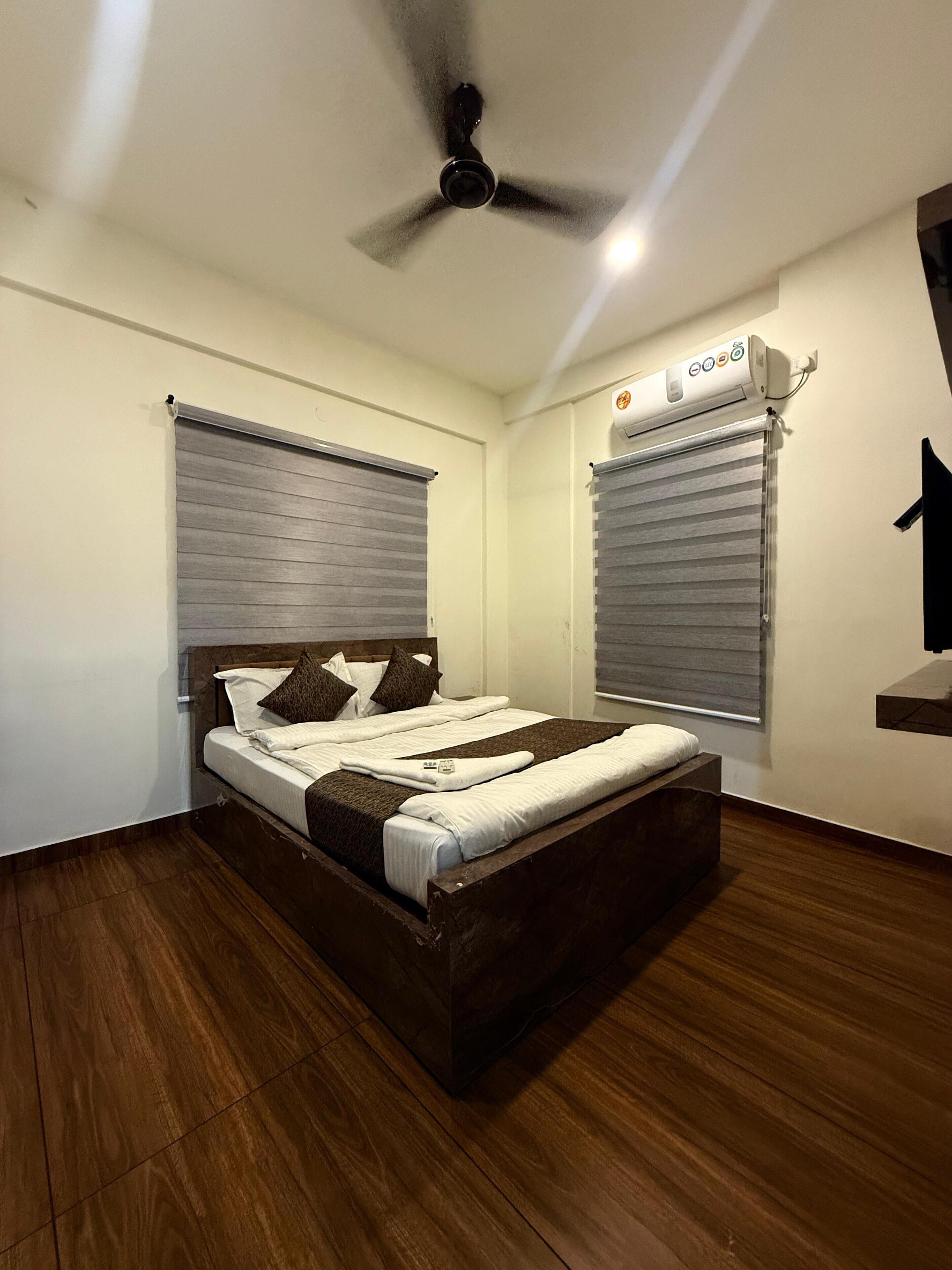 Ein Schlafzimmer mit einem hölzernen Bett, einem Deckenventilator und einem Fenster mit Jalousien.