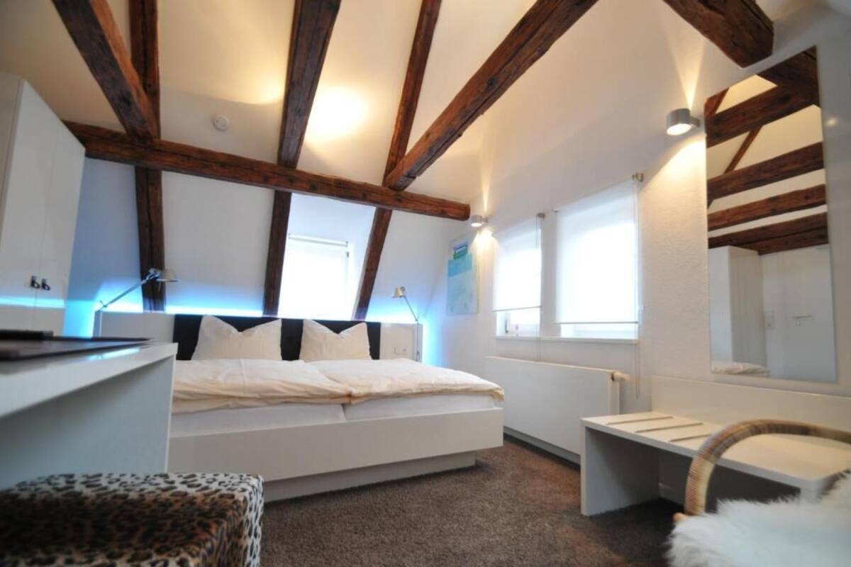 A bedroom with a bed, a chair, a desk, and a window.