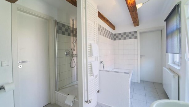 Une salle de bain avec douche, toilettes et baignoire.