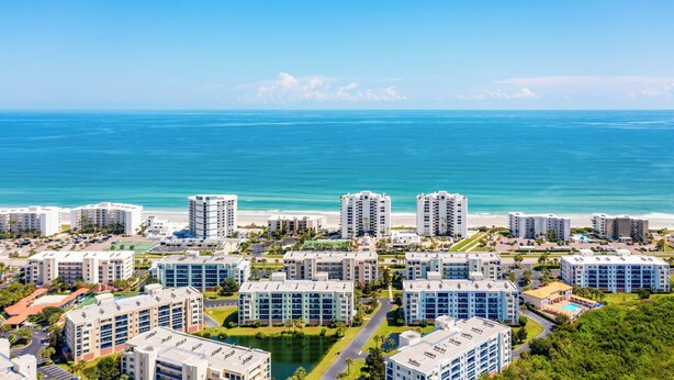 Zona residencial costera con varios edificios altos, una playa y cielo azul despejado.
