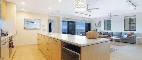 A modern kitchen with a large island, built-in appliances, and a view to the outside.