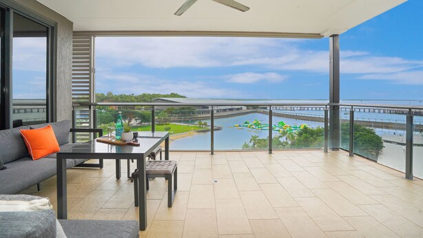 Un balcon offrant une vue sur une étendue d’eau, un pont et une côte lointaine.
