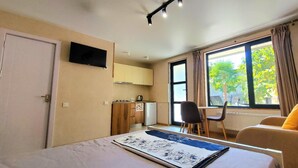 Une chambre d’hôtel équipée d’un lit, d’un bureau, d’une chaise, d’un canapé, d’une télévision et d’une fenêtre avec des rideaux.