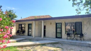 Une maison à deux étages dotée d’un patio, d’un porche couvert et d’un petit jardin agrémenté de fleurs roses.