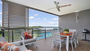 Ein Balkon mit Tisch und Stühlen, einem Deckenventilator und Blick auf ein Gewässer.