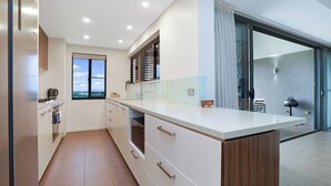 Eine moderne Küche mit einer großen Kochinsel, einem Einbauofen und Blick durch das Fenster.