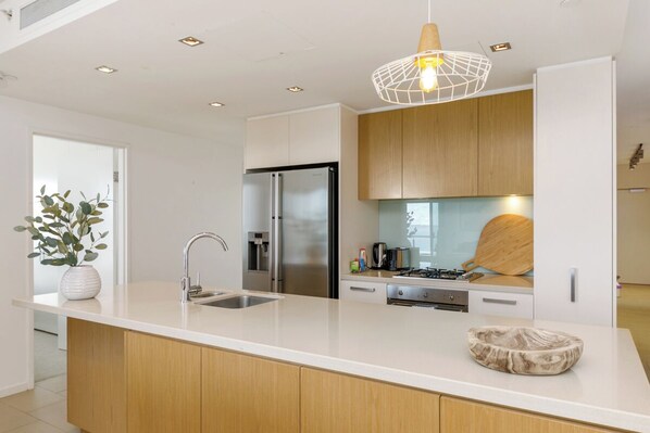 A modern kitchen with a large island, stainless steel appliances, and a pendant light.