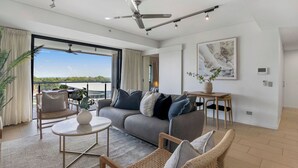 Een moderne woonkamer met een bank, stoelen, een salontafel en uitzicht op de omgeving.