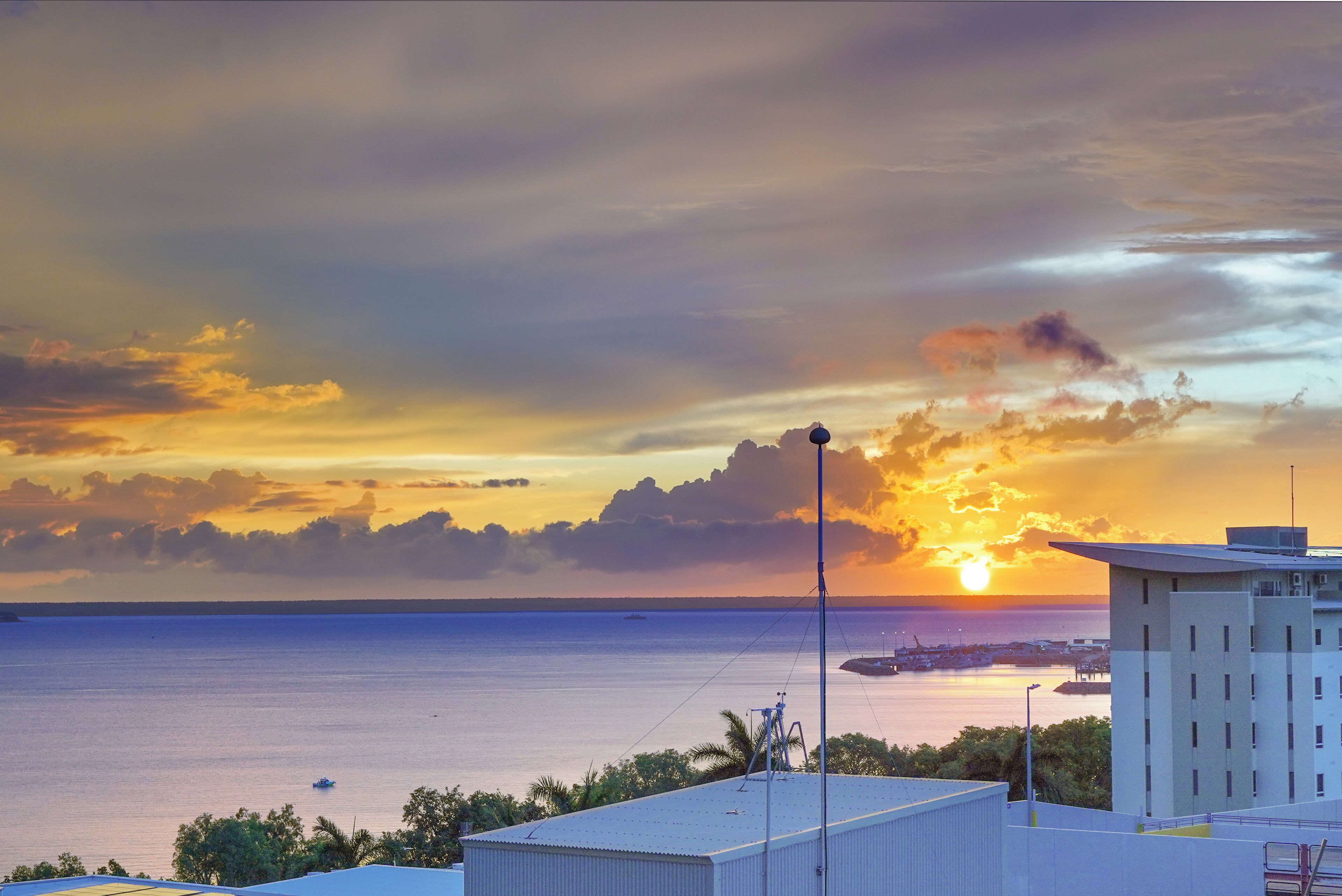 Une vue sur la côte, avec un coucher de soleil, des bâtiments et un ciel dégagé.