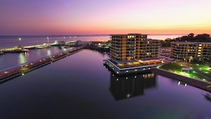 Un hôtel situé au bord de l’eau, doté d’un design moderne, avec un bâtiment principal à plusieurs étages et un toit plat.