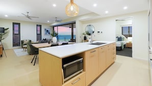 Une cuisine moderne dotée d’un grand îlot central, d’un four à micro-ondes encastré et d’un ventilateur de plafond.