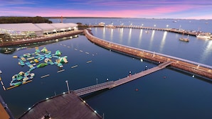 Une zone riveraine dotée d’un quai, d’une structure flottante avec des toboggans et d’un bâtiment à grand toit.
