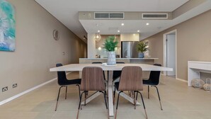 A modern kitchen with a central island, built-in appliances, and a dining area with a table and chairs. - Enchanting Waterfront Lagoon Views + Restaurants (Darwin)
