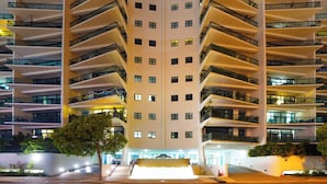 Um edifício moderno de vários andares, com varandas e uma entrada central.