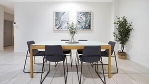 En matplats med ett vitt bord, svarta stolar och två inramade tavlor på väggen.