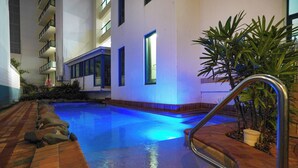 An indoor swimming pool with a tiled edge, a metal handrail, and a potted plant near the pool's edge. - Scenic CBD Getaway, Harbour Views, Pool/Gym, Cafes (Darwin)
