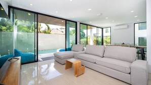 A modern living room with a large sectional sofa, a wooden coffee table, and a glass sliding door leading to a balcony.
