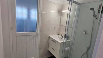 Een douche, handdoeken, zeep, toiletpapier