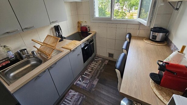 Cocina compacta con armarios grises, encimera de madera, un lavamanos y una ventana con vistas a la vegetación.