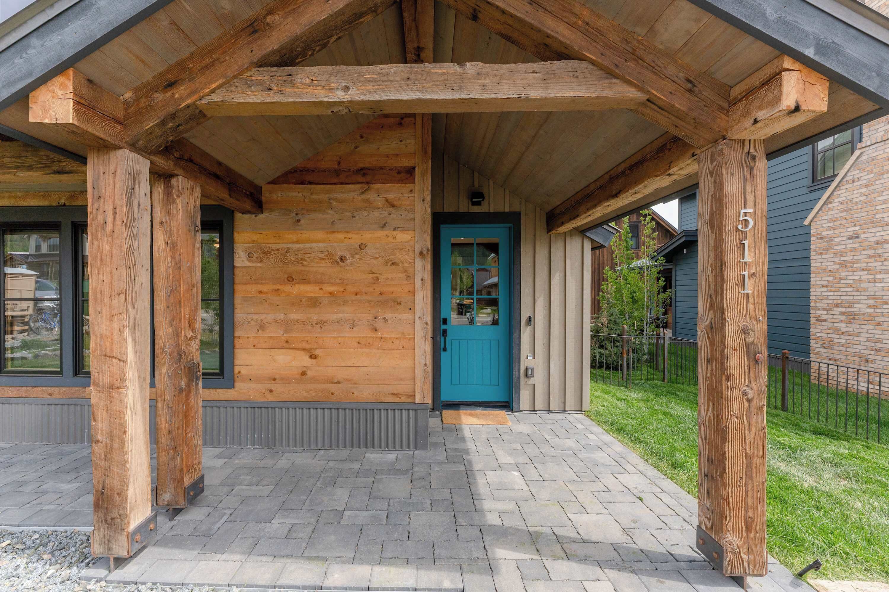 A wooden cabin with a blue door, a covered porch, and a brick pathway.