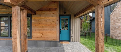 A wooden cabin with a blue door, a covered porch, and a brick pathway.