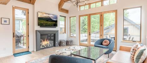 A spacious living room with a fireplace, large windows, and a cozy seating area.