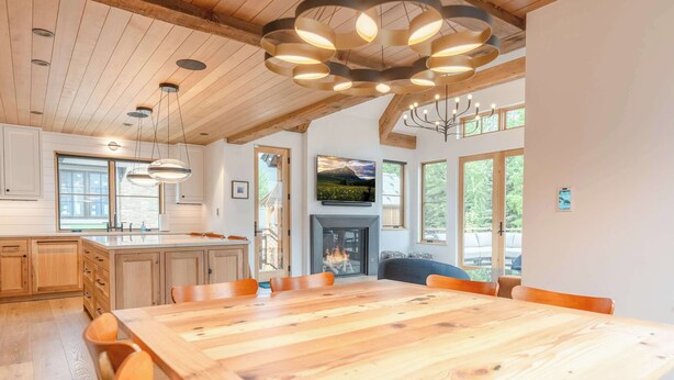 A spacious kitchen with wooden cabinets, a large dining table, and a fireplace. - Teocalli Art House, new, hot tub, walk everywhere! (Crested Butte)