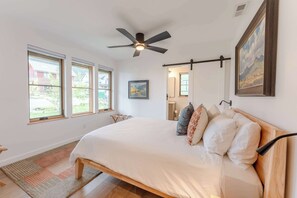 A bedroom with a bed, a ceiling fan, and three windows.