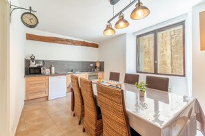 A modern kitchen with a dining area, wooden ceiling beams, and a large window. - Holiday Home ‘La Bonbonnière’ – Charm and Comfort at the Foot of Mont Ventoux (Malaucène)