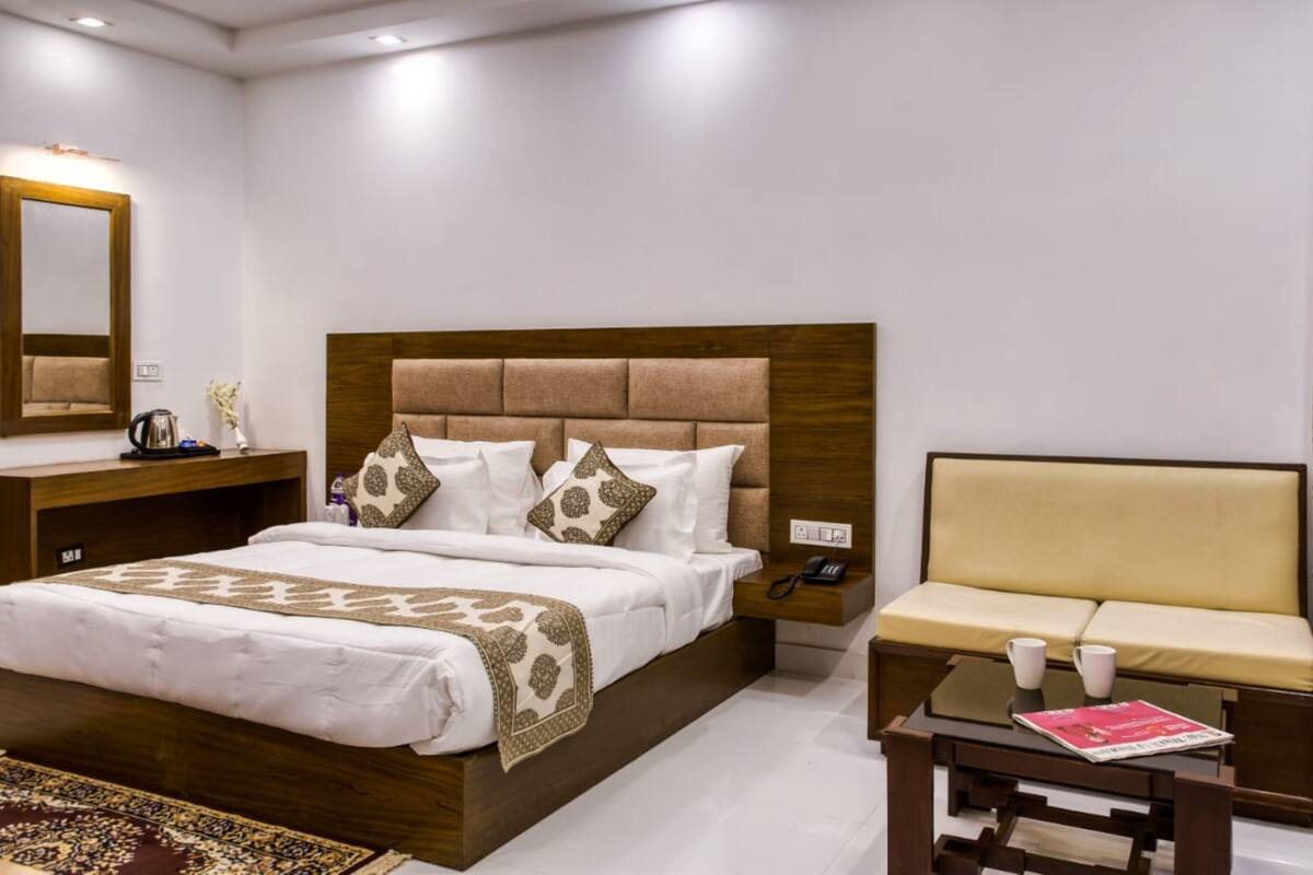 Une chambre d’hôtel avec un grand lit, une table de chevet avec un téléphone, un canapé et une table basse.