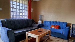 Ein Wohnzimmer mit zwei Sofas, einem Couchtisch, einem Wasserspender und einer TV-Konsole.