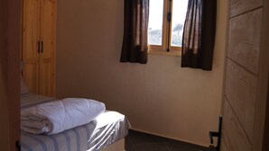 A bedroom with a bed, a window with curtains, a hanging light fixture, and a wooden wardrobe. - Labri de la Plage (Sidi Kaouki)