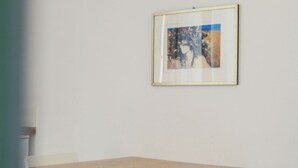 A small dining area with a wooden table and two white chairs. A framed artwork is hung on the wall above the table. - Small-scale apartment with garden (Venezia)