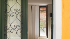 An open door leading to a patio with a brick wall and a green chair. - Small-scale apartment with garden (Venezia)