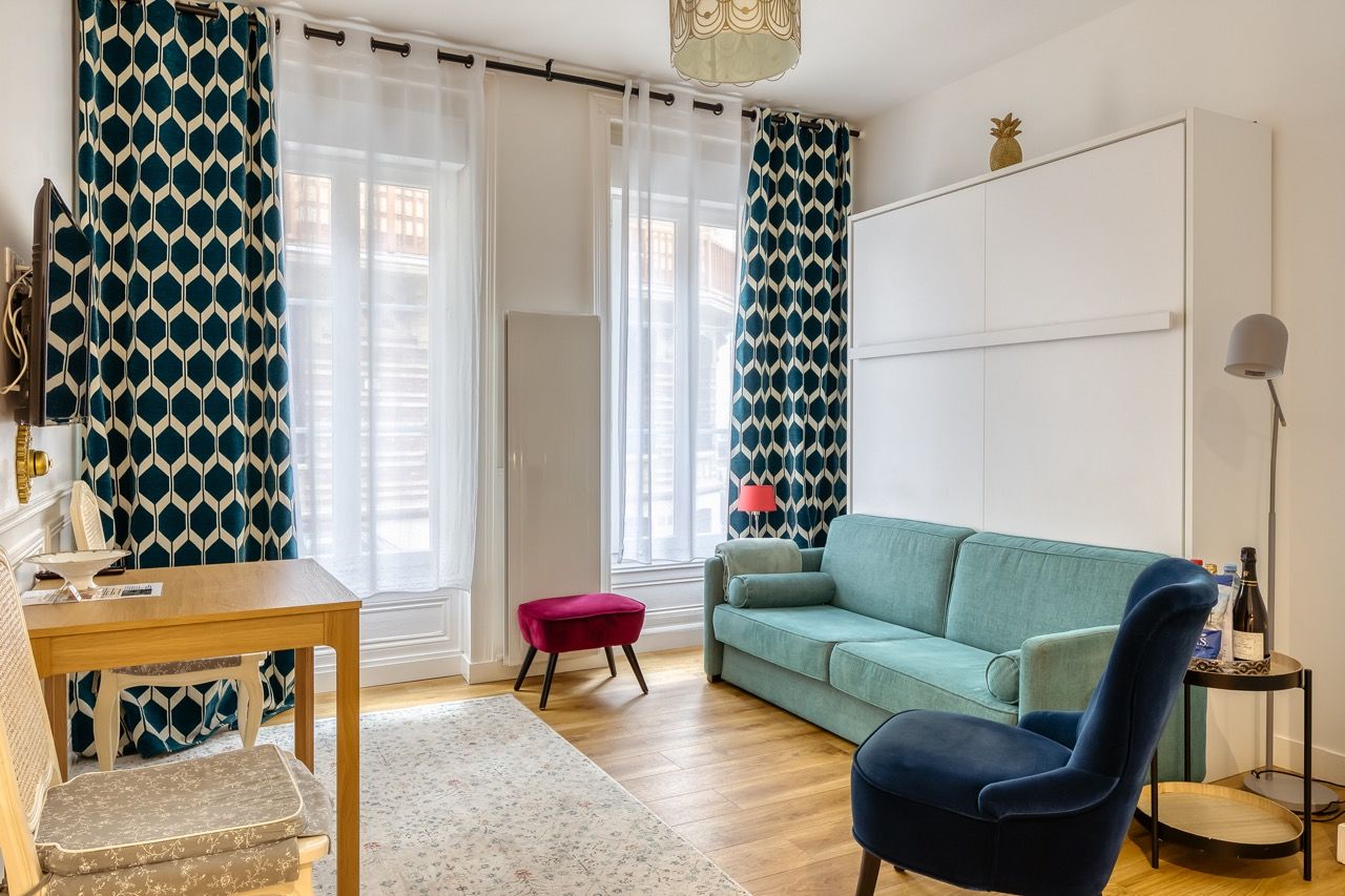 Ein Wohnzimmer mit einer Couch, einem Sessel, einem kleinen Tisch und einer Lampe.