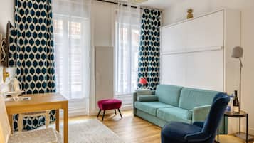 Ein Wohnzimmer mit einer Couch, einem Sessel, einem kleinen Tisch und einer Lampe.