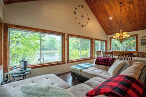 A cozy room with a large window, a chandelier, and a bed with a blanket.
