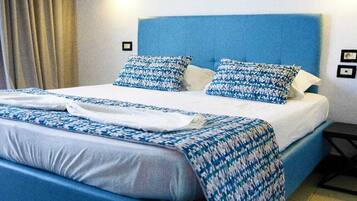 Cama bem arrumada com cabeceira azul e roupa de cama estampada.