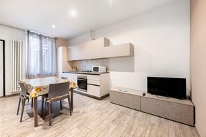 Una cucina moderna con un tavolo da pranzo, sedie, un forno a microonde e una televisione.