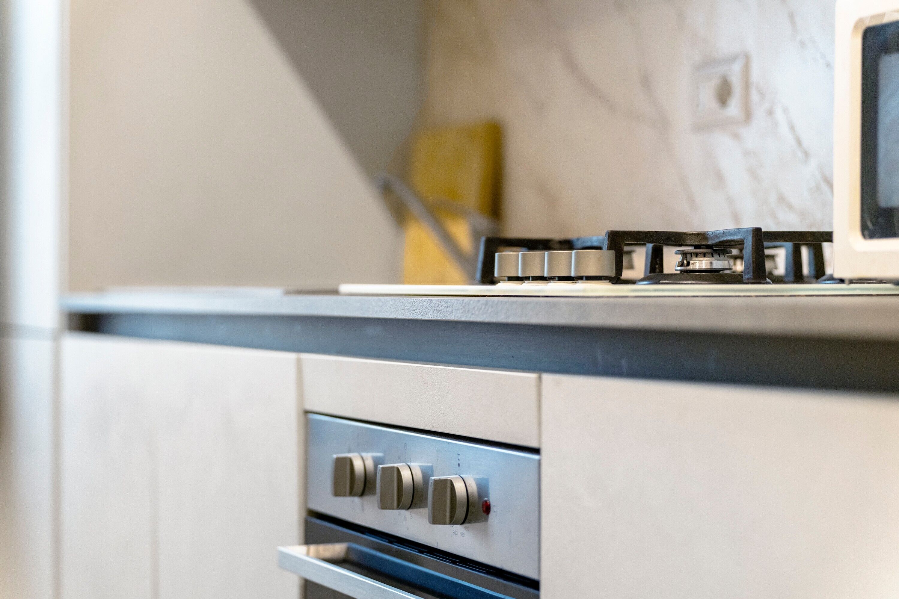 A kitchen with a gas stove, a microwave, and a stainless steel oven.