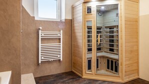 Une chambre d’angle avec un sauna, une fenêtre et un radiateur blanc.
