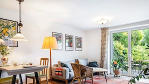 Une pièce comprenant une table à manger, des chaises, un canapé, une lampe et une grande fenêtre donnant sur un paysage verdoyant.