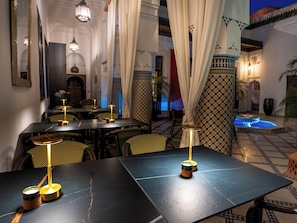 Un comedor con mesas, sillas e iluminación ambiental.