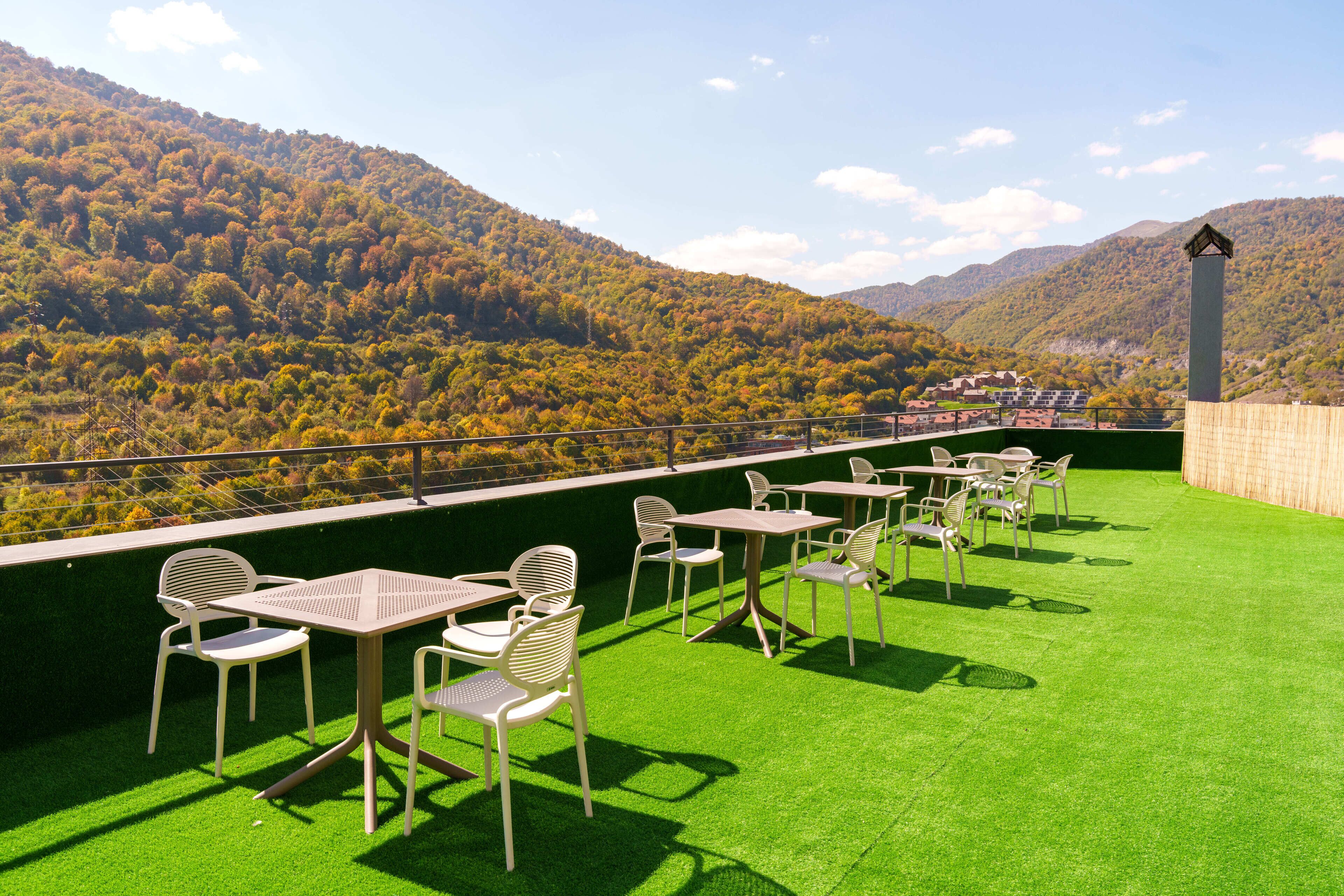An outdoor seating area with tables and chairs, overlooking a mountainous landscape.
