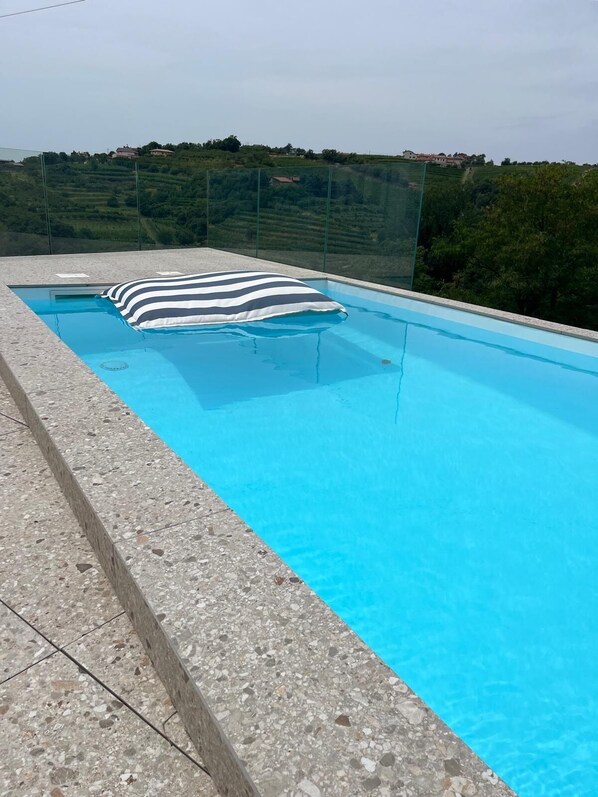 Una piscina rectangular con una barrera de vidrio y una toalla a rayas.