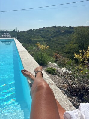 Vista a la piscina bajo un cielo despejado, con piscina y un paisaje de campos verdes y árboles.