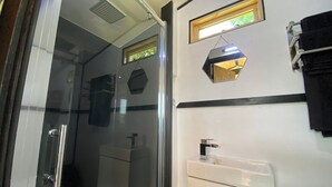 Une salle de bain avec une douche à parois de verre, un lavabo blanc et un porte-serviettes.