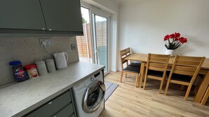 Een praktische keuken met een wasmachine, een eethoek met houten stoelen en een kleine tafel.