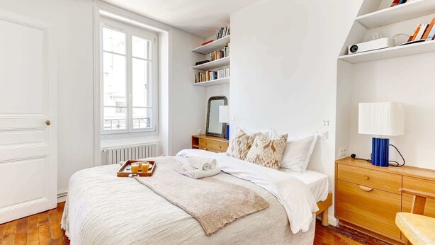 Une chambre à coucher bien rangée, avec un lit, une table de chevet et une fenêtre.
