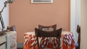 A dining area with a table covered by a patterned tablecloth, a chair with a metal bowl on the backrest, and a vintage-style lamp on a side table. - Apartment in the center of Venice (Venezia)